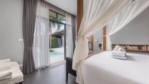 A hotel room with a bed, a bedside table, a window with sheer curtains, and a view of an outdoor pool area. - Villa Kiana Private Pool 10 min Nai Harn (Rawai)