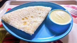Une assiette bleue avec une crêpe blanche et un bol de sauce jaune.