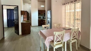 A dining area with a table set for four, a kitchen in the background, and a door leading to another room. - Casa Terracota: Lovely 3-bedroom house in Atenas Perfect for Relaxing Getaways (Atenas)