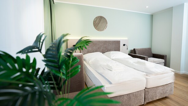 A modern bedroom with a bed, bedside table, and a round wall decoration. - Living Inn (Rheda-Wiedenbrück)