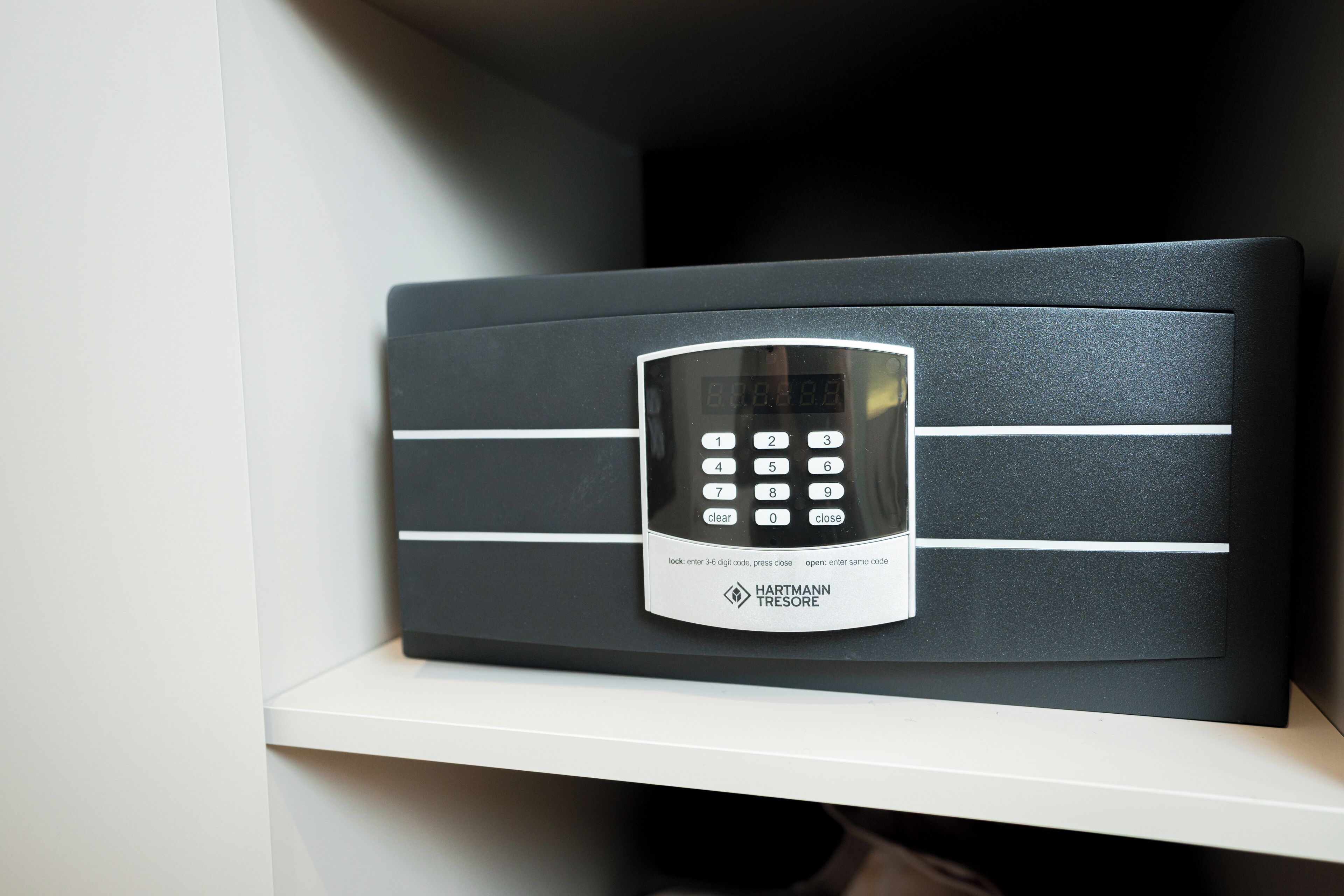 A security keypad on a black panel with a white shelf below.