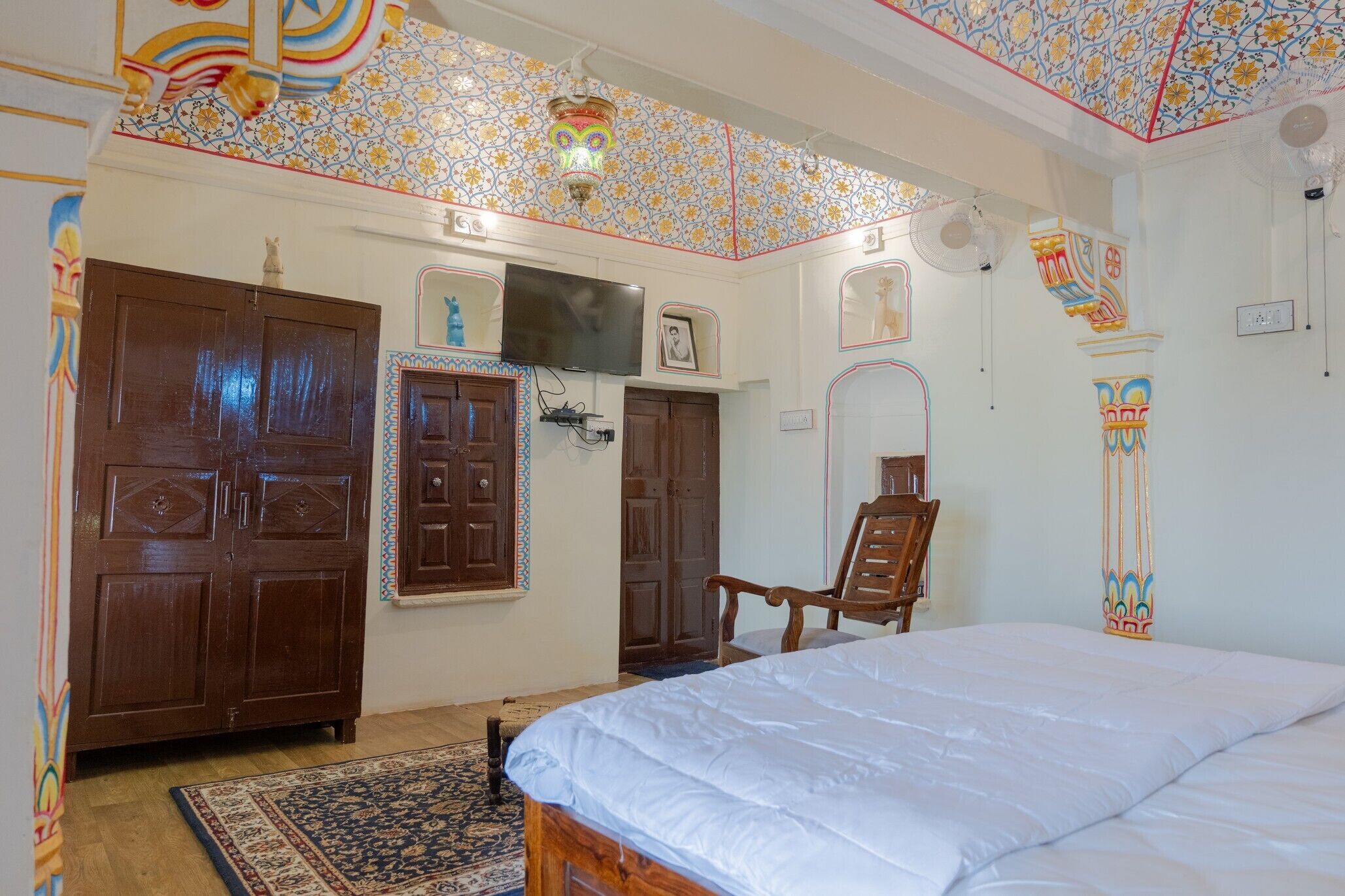 A bedroom with a large bed, two wooden doors, a television, and a chair.