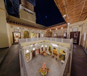 Un amplio patio con una fuente central, rodeado de arquitectura tradicional y varias zonas de estar.