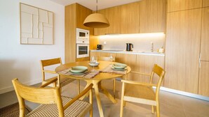 A modern kitchen with wooden cabinets, a round dining table, and four chairs. - Carvoeira Nature & Serenity Escape by Lisbeyond (Barril)