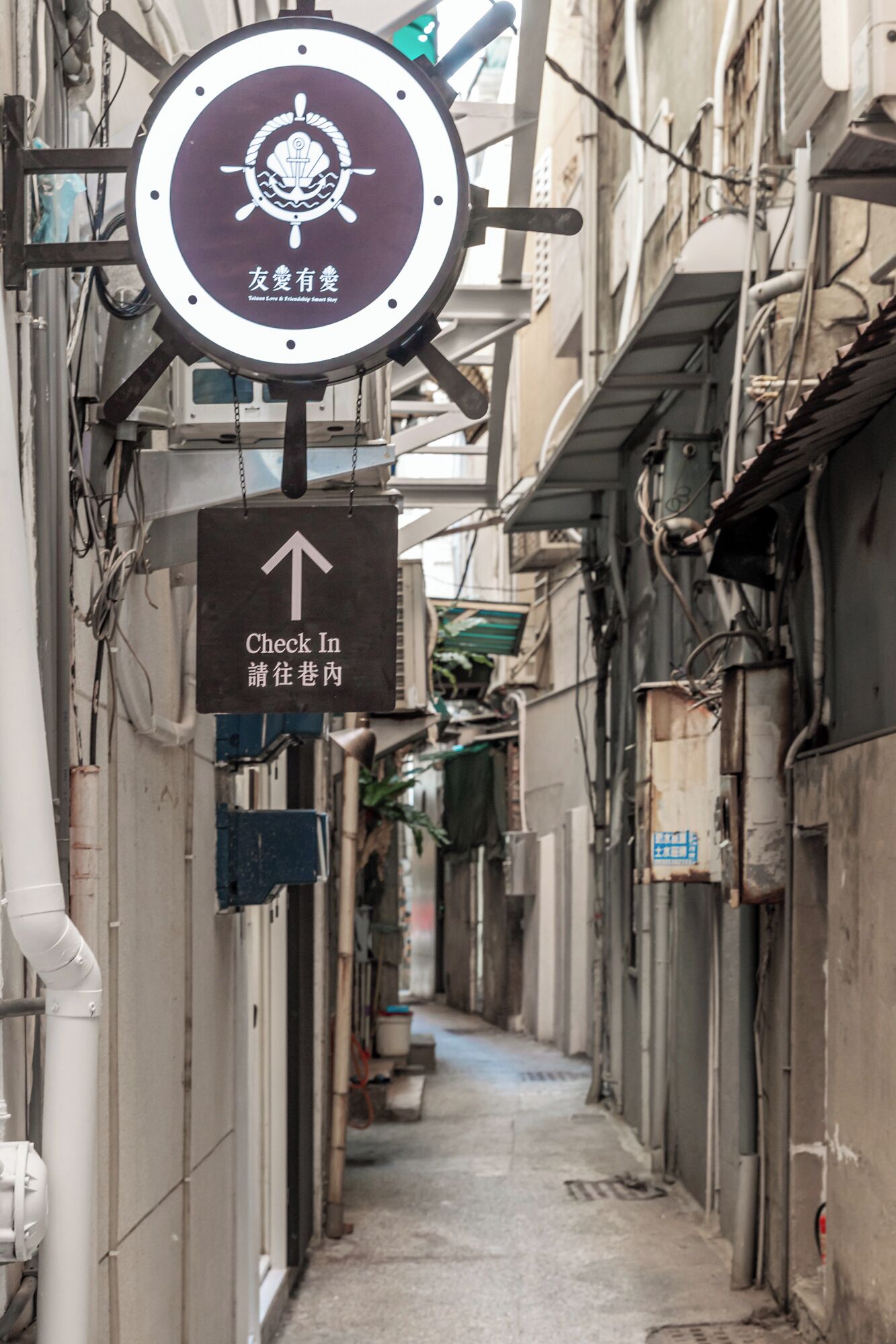 A narrow alleyway with a sign indicating a direction to check in.