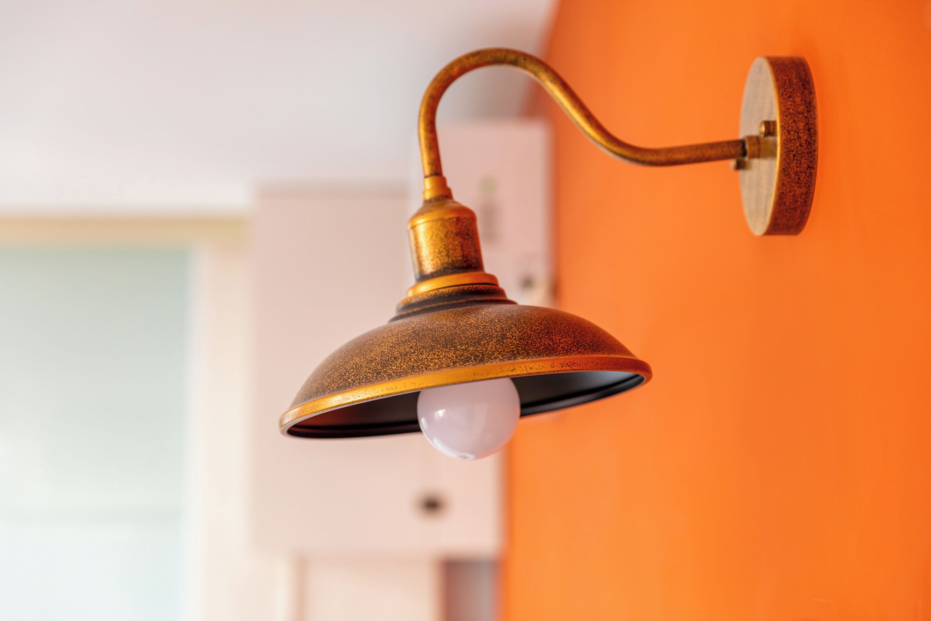 A wall-mounted light fixture with a curved arm and a visible bulb.