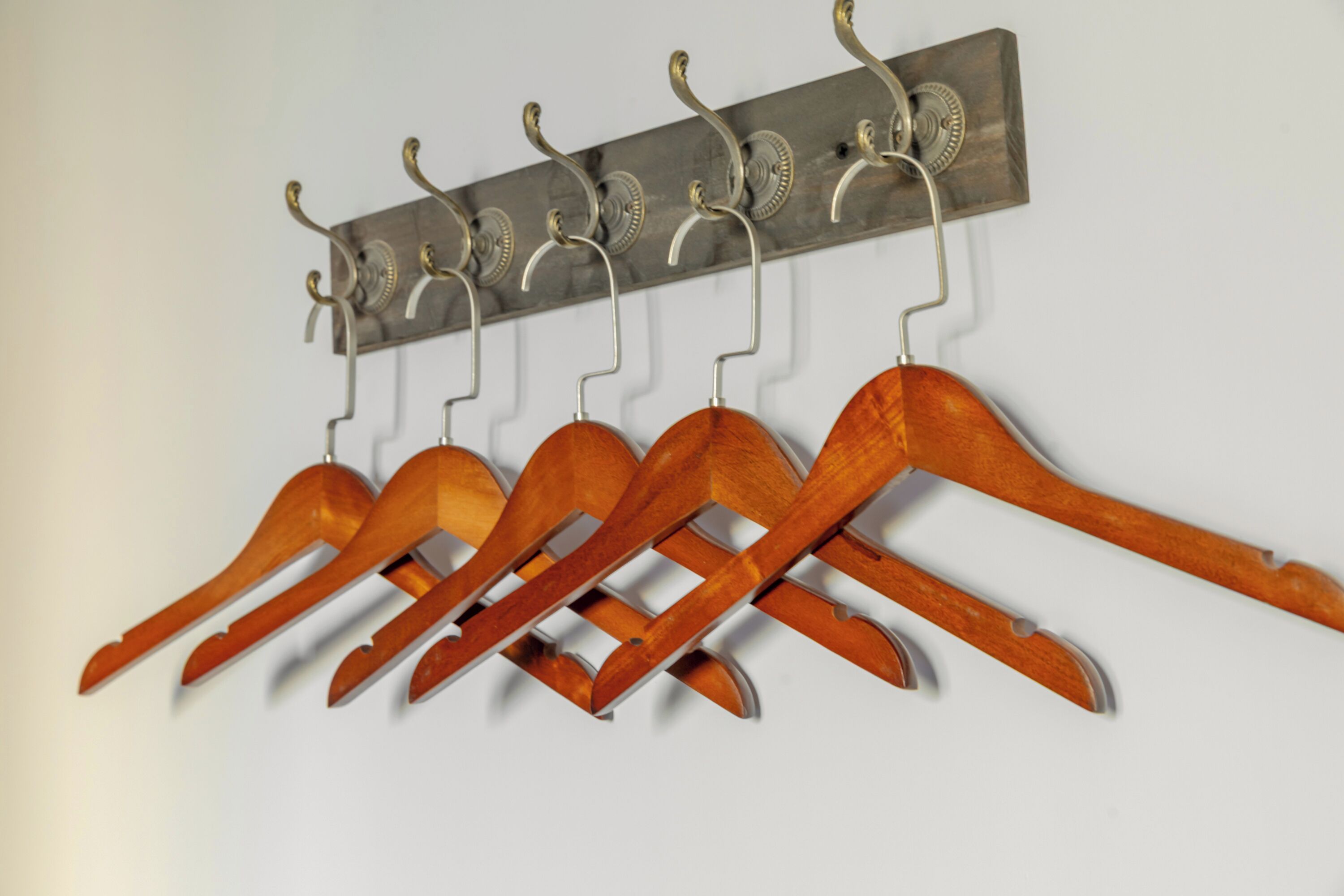 A wall-mounted coat rack with multiple wooden hangers.