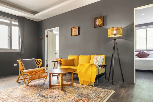 A room with a sofa, a chair, a floor lamp, and a patterned rug. - Tainan Love & Friendship Smart Stay (Tainan)