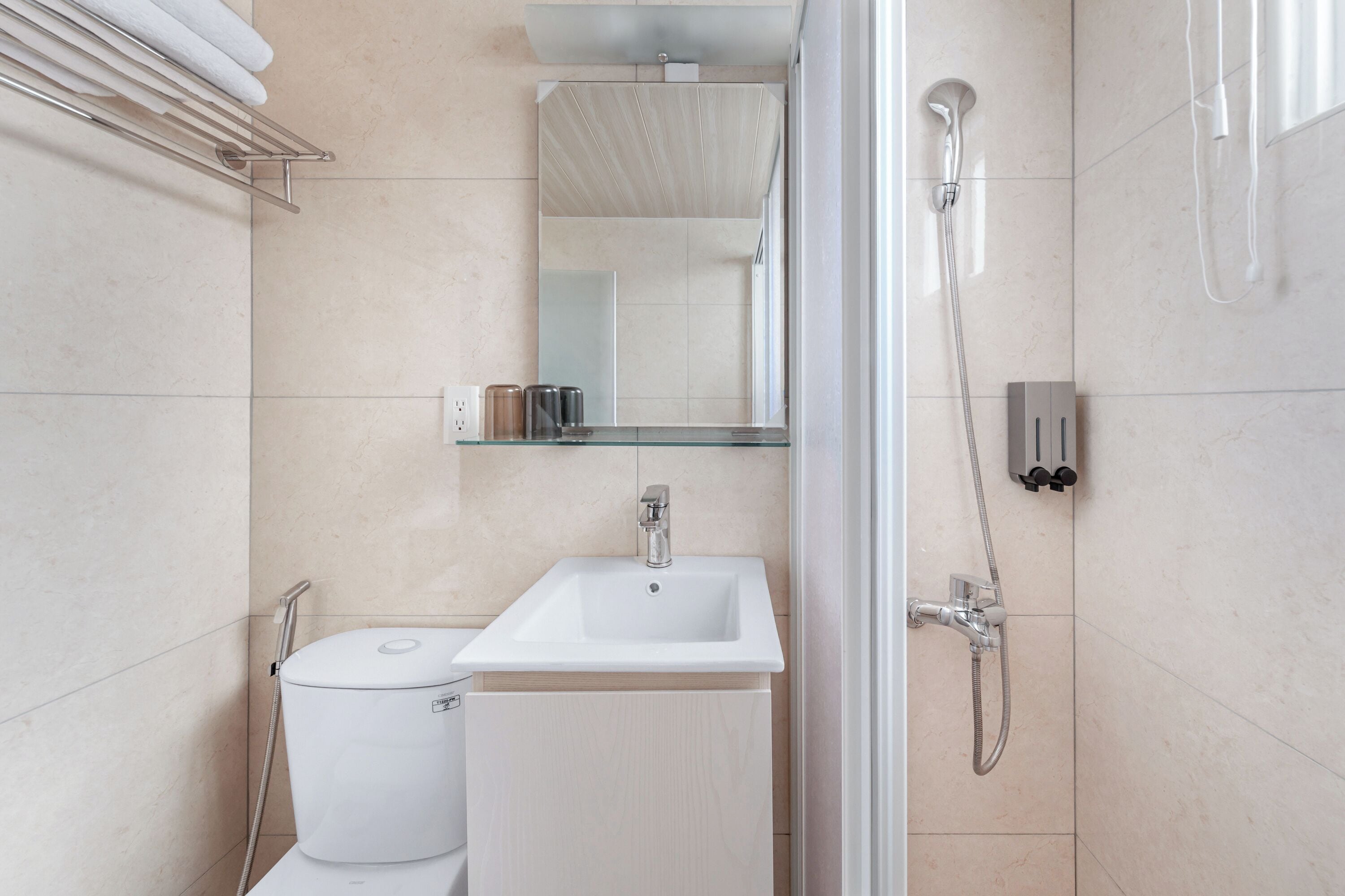 A modern bathroom with a white sink, a toilet, a shower, and a towel rack.