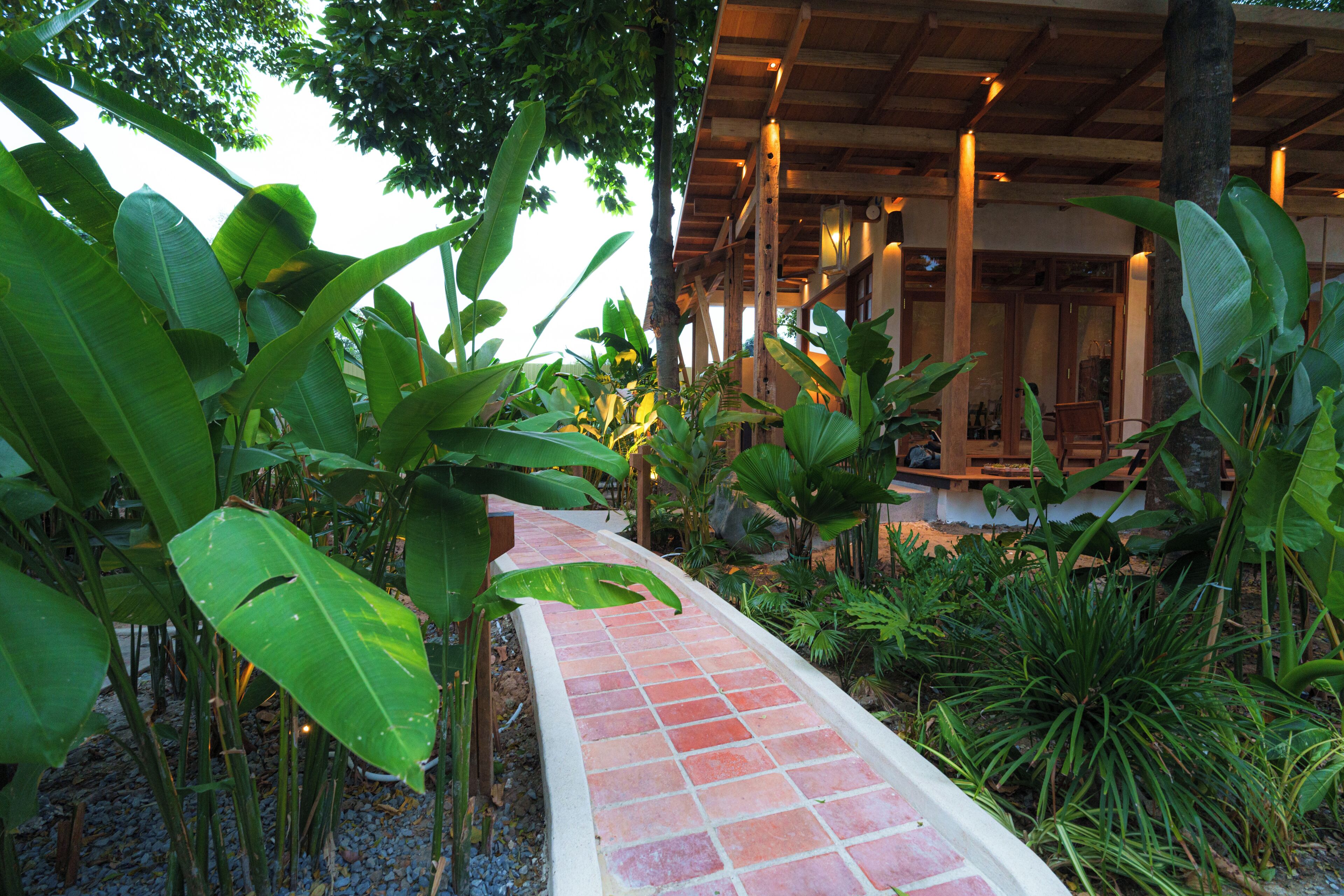 A pathway leading to a covered area with wooden beams and a brick floor.