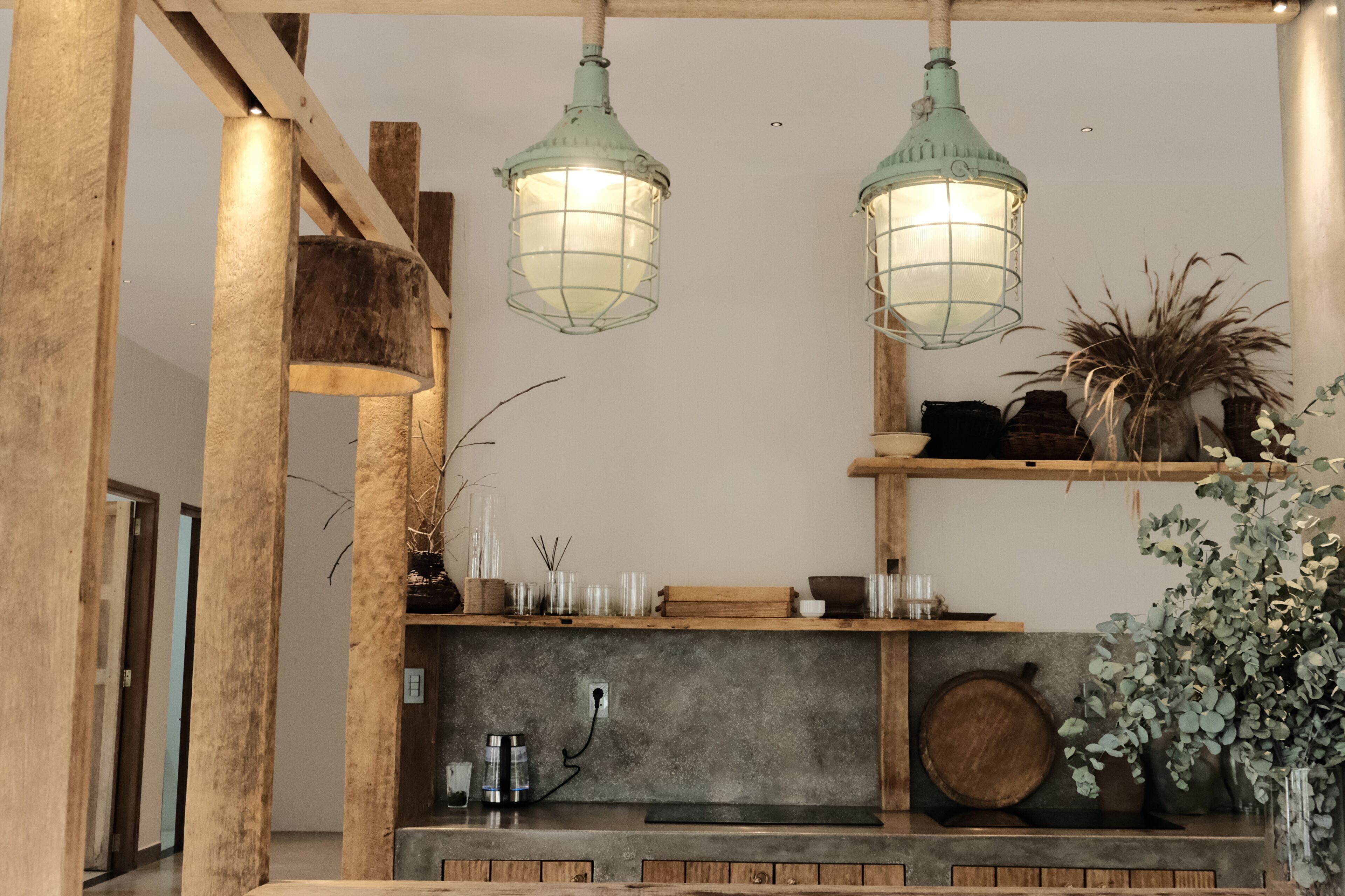 Una estantería de madera con objetos decorativos, una lámpara colgante y una planta.