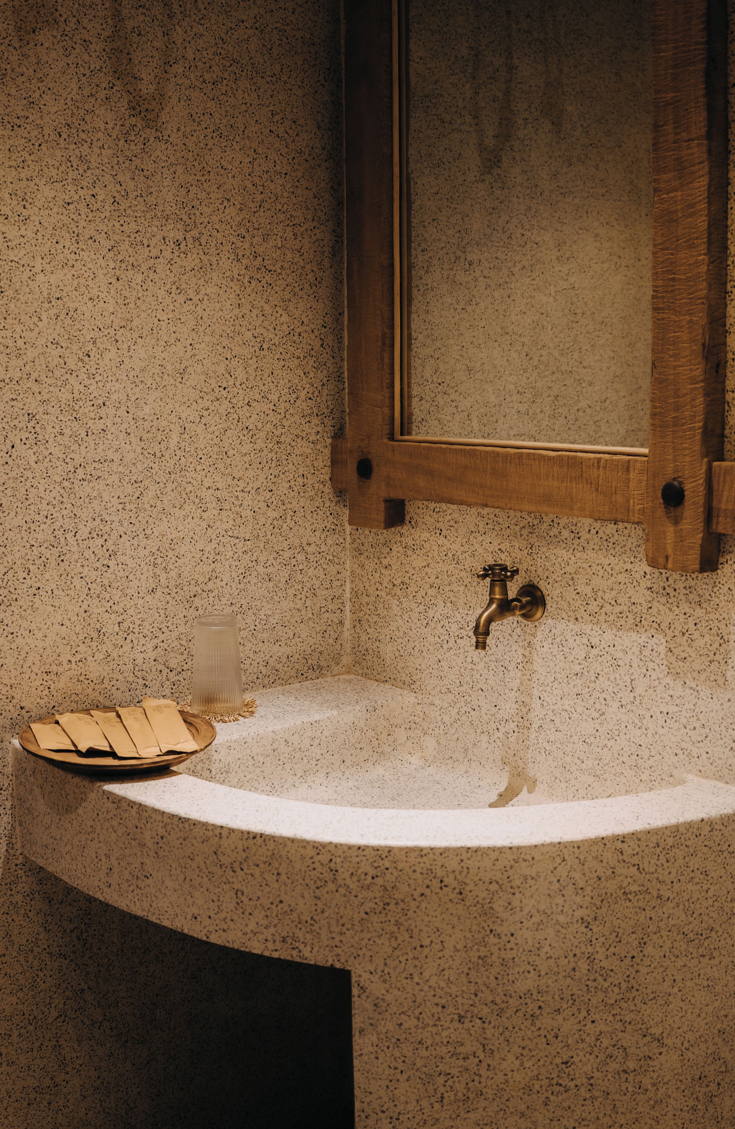 Une salle de bain avec un lavabo en pierre à motifs, un meuble en bois et un miroir.