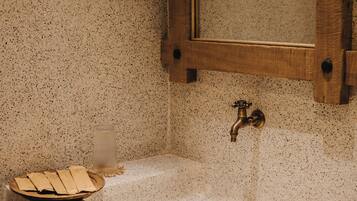 Une salle de bain avec un lavabo en pierre à motifs, un meuble en bois et un miroir.