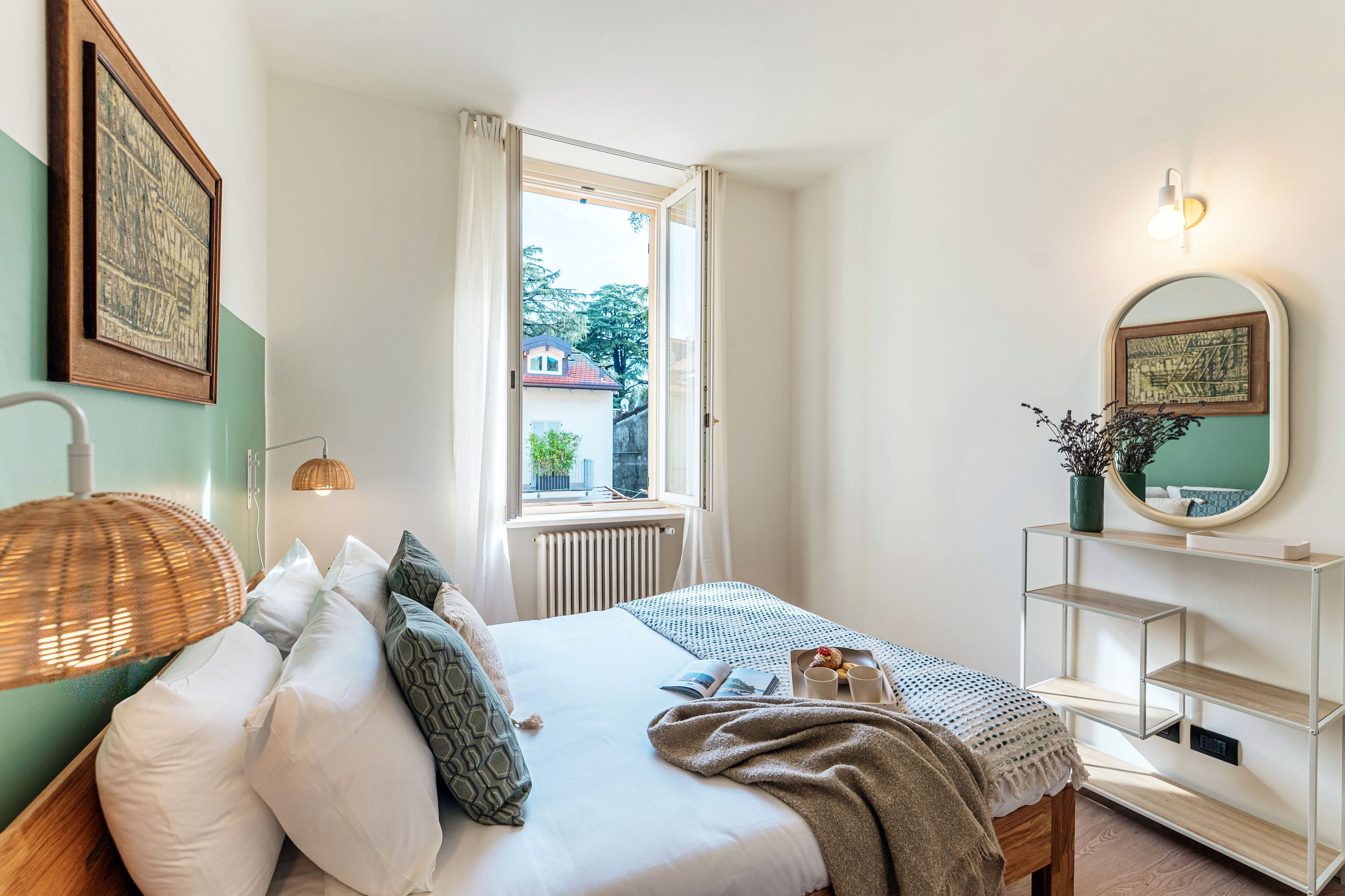 A neatly arranged bedroom with a bed, bedside table, and a window with curtains.