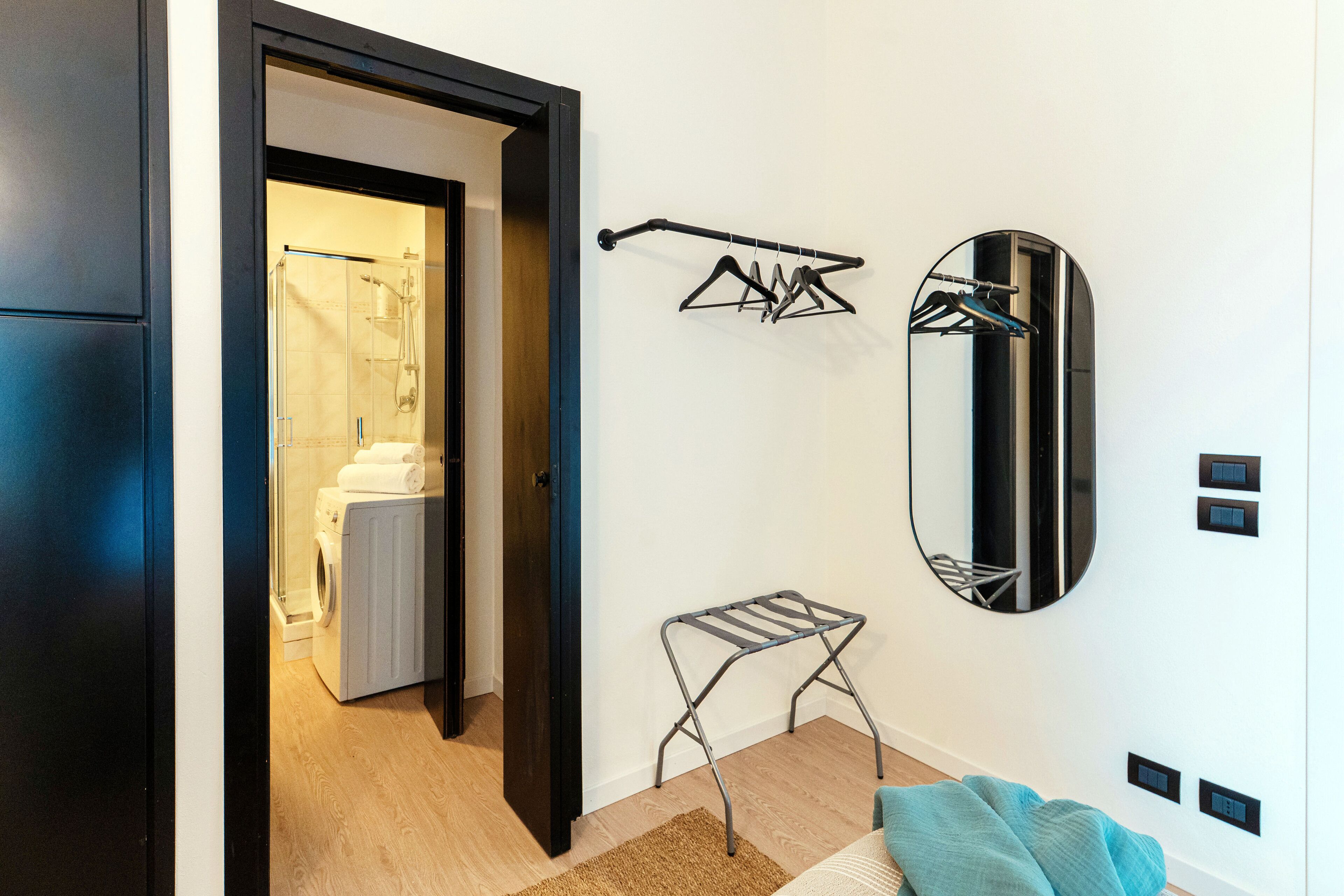 Ein modernes Badezimmer mit Duschkabine aus Glas, einer Waschmaschine, einem Wäscheständer und einem wandmontierten Spiegel.