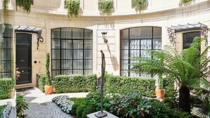 A courtyard with a black door, potted plants, and a statue. - Maison Bauchart (Paris)