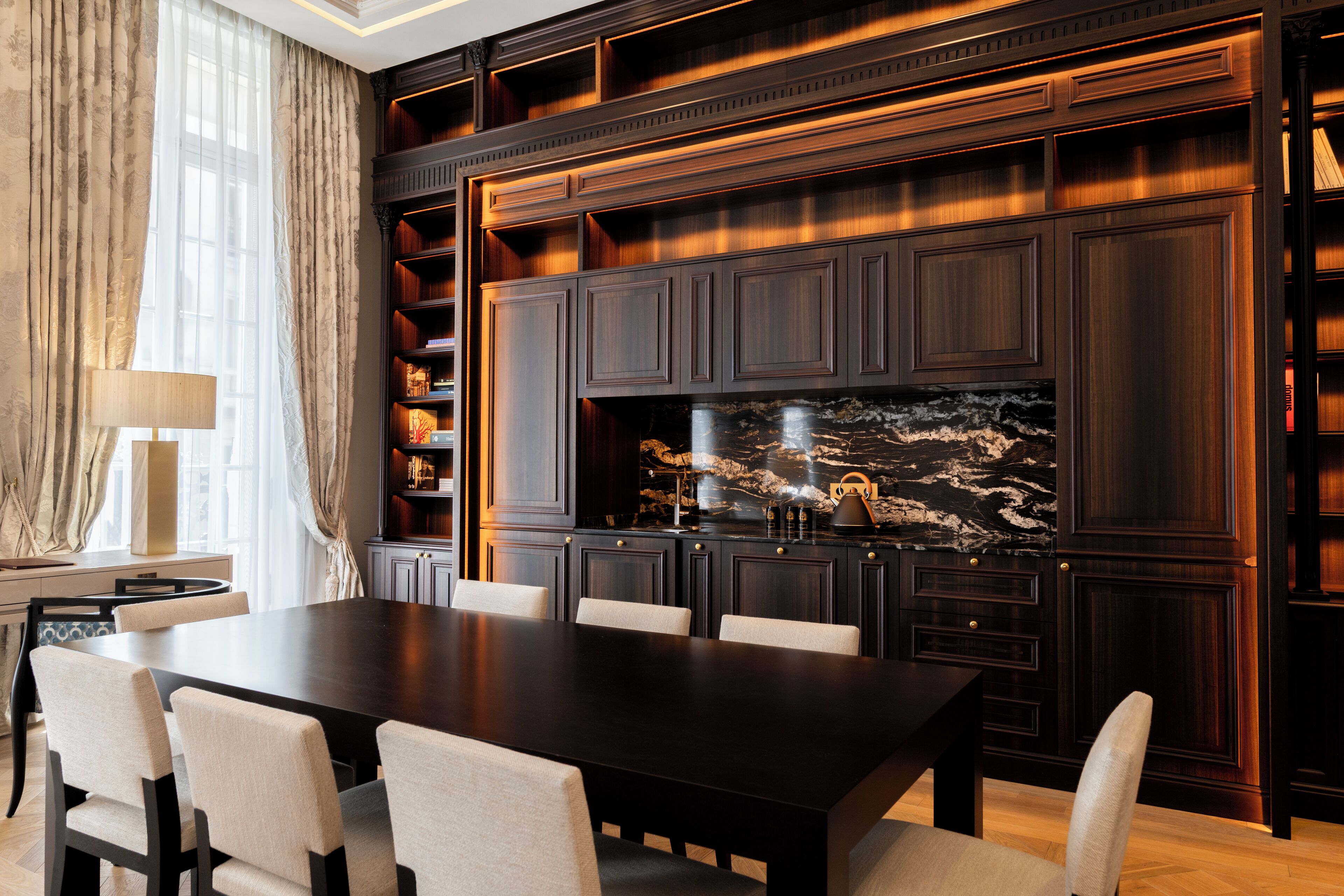 A formal dining room with a dark wooden table, six chairs, and built-in bookshelves.