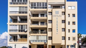 Un edificio a più piani con balconi, un cartello con la scritta 'Livadiotis Property Developers' e un segnale di 'Stop'.