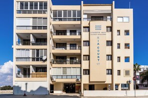 Een meerhoog gebouw met balkons, een bord met 'Livadiotis Property Developers' en een stopbord.