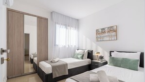 Una camera d'albergo con due letti, un grande specchio, un quadro e una porta con stipite in legno.