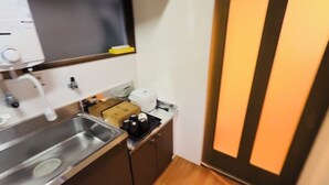 Une cuisine compacte équipée d’un évier en acier inoxydable, d’une machine à café et d’un grille-pain.