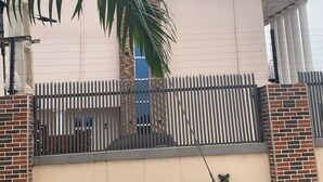 A building with a sign reading "COMFORT KUL SUITES" and a gated entrance with a palm tree in the foreground.