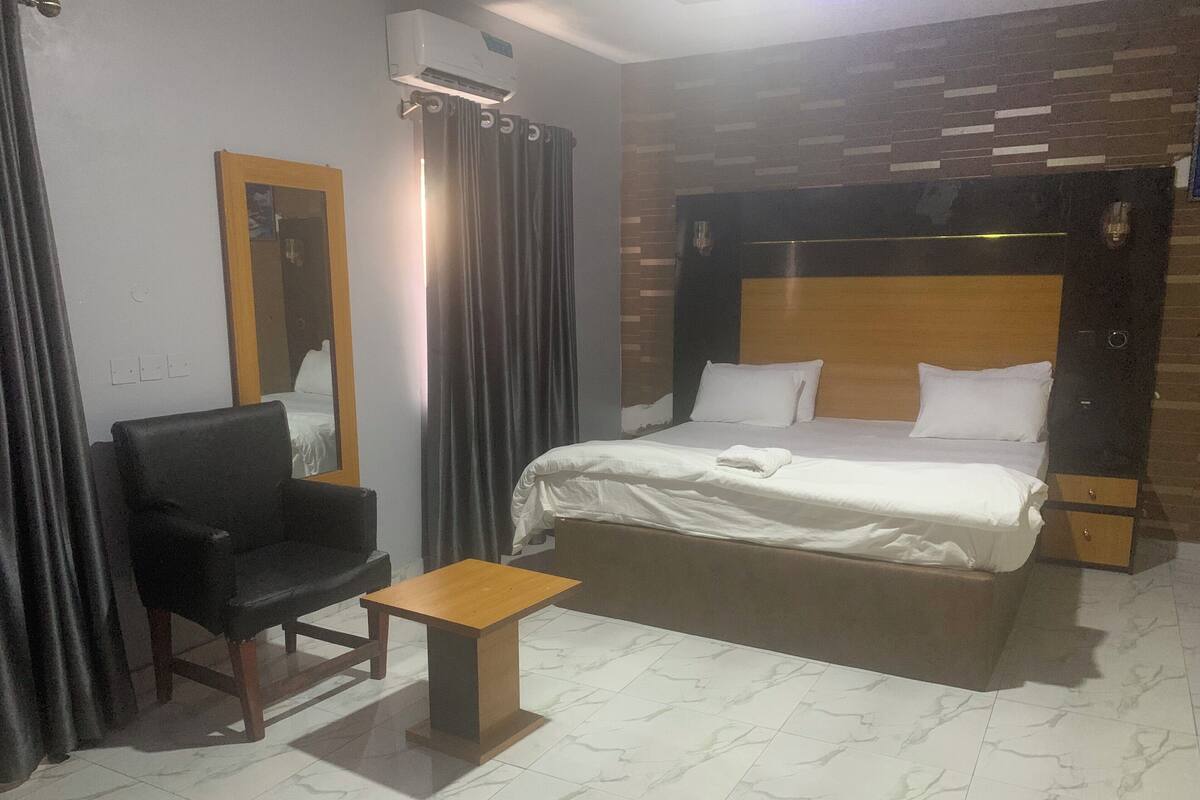 Ein Hotelzimmer mit Bett, Sessel, kleinem Tisch und Spiegel.