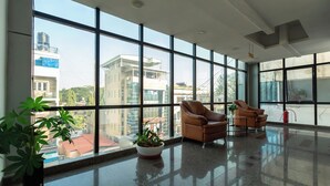 Eine geräumige Lobby mit großen Fenstern, zwei Ledersessel und einem Blumentopf.