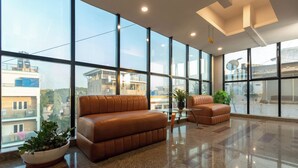 Eine geräumige Lobby mit großen Fenstern, einem braunen Ledersofa und einem Blumentopf.