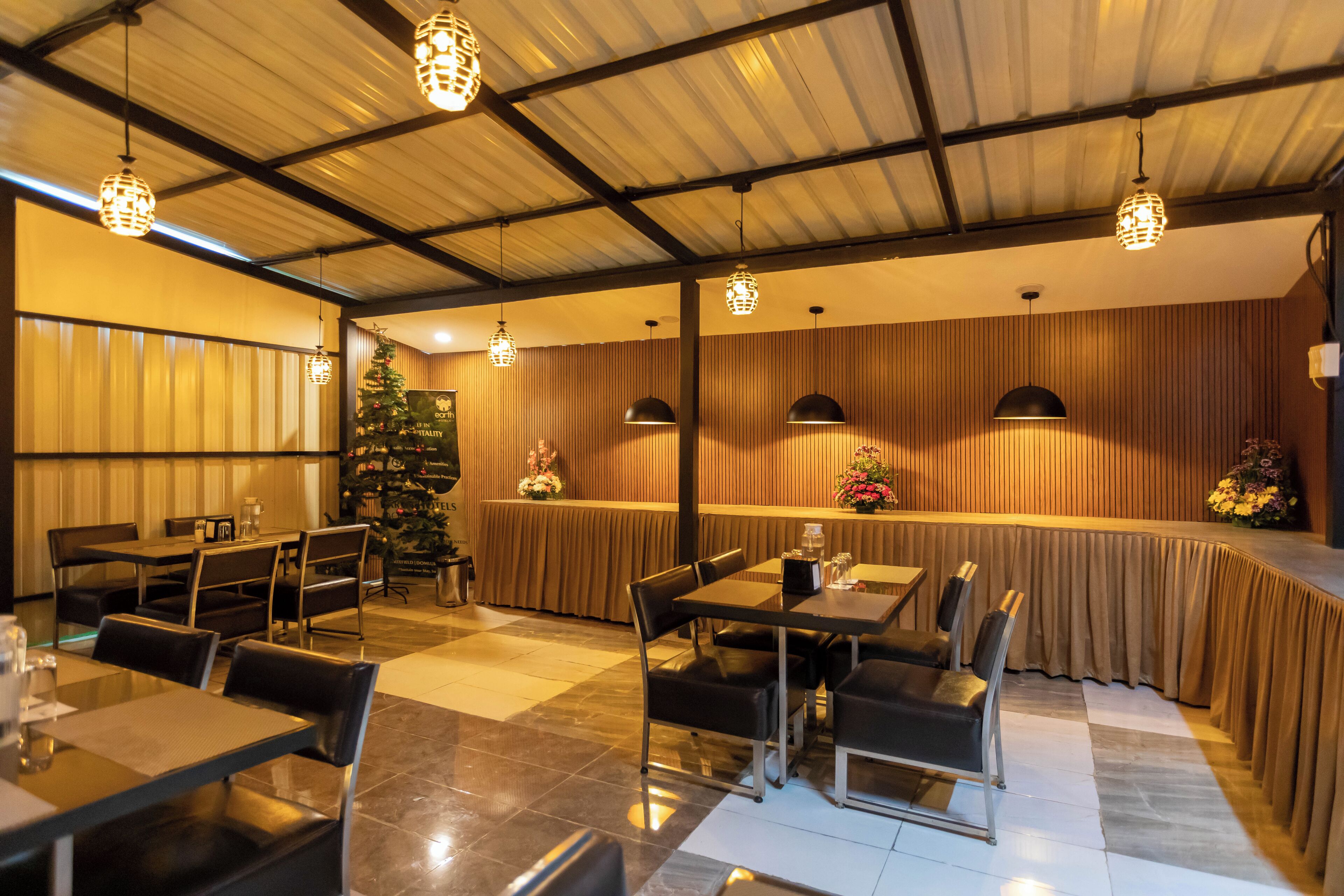 A restaurant with tables and chairs, a Christmas tree, and hanging lights.
