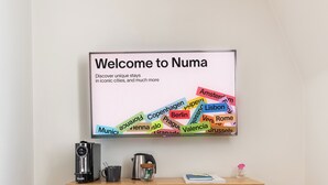 Un escritorio con un cartel de bienvenida que enumera ciudades como Ámsterdam, Copenhague y Berlín.