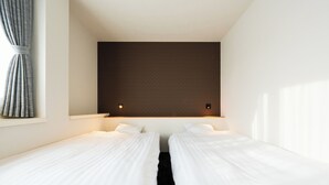 A hotel room with two single beds, a dark headboard, a window with curtains, and a wall-mounted light fixture. - SPACEPORT HOTEL OITA (Kunisaki)