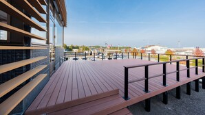 A wooden deck with benches and a railing, overlooking a parking area and buildings. - SPACEPORT HOTEL OITA (Kunisaki)