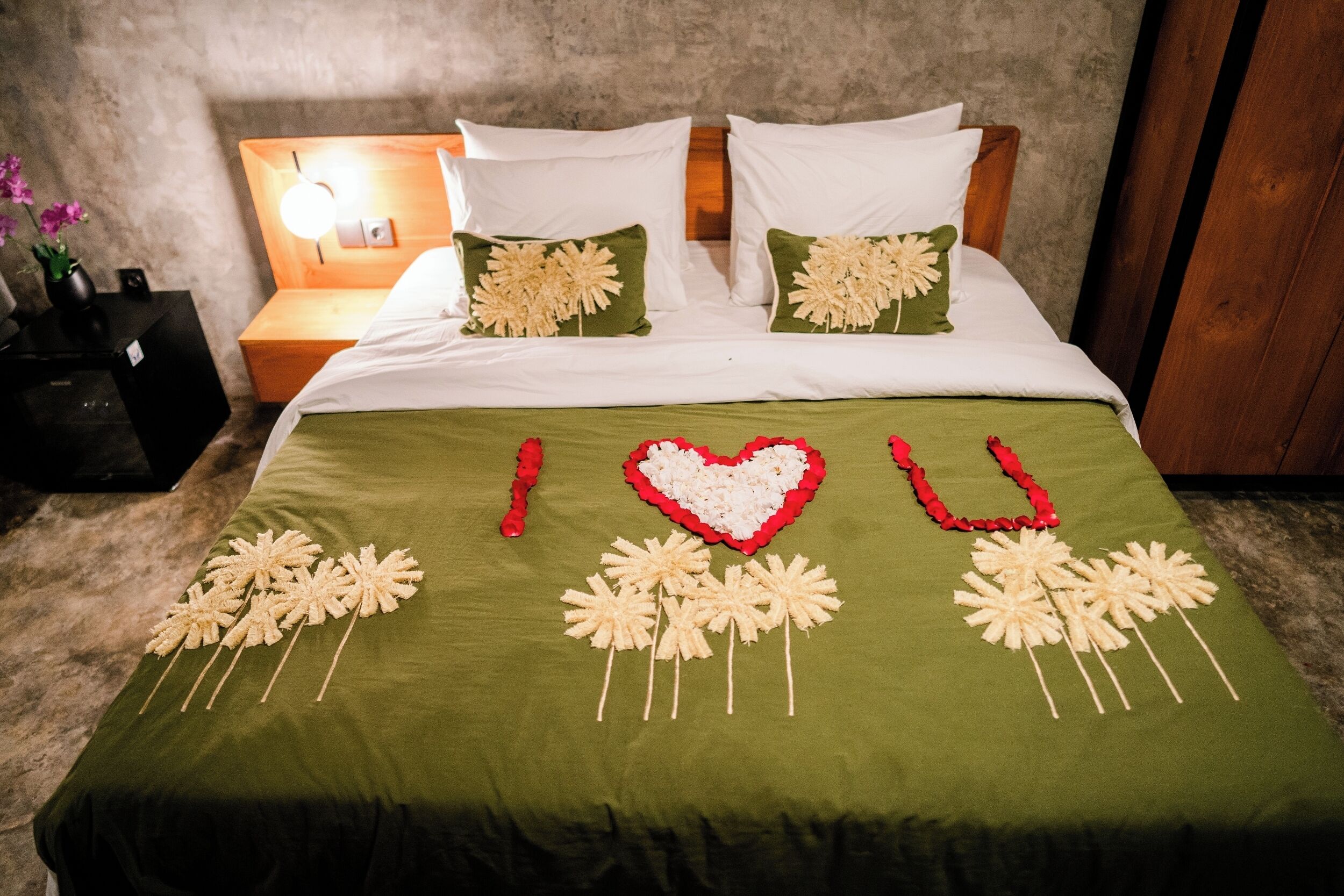 Un llit amb roba de llit verda i adorns florals decoratius.