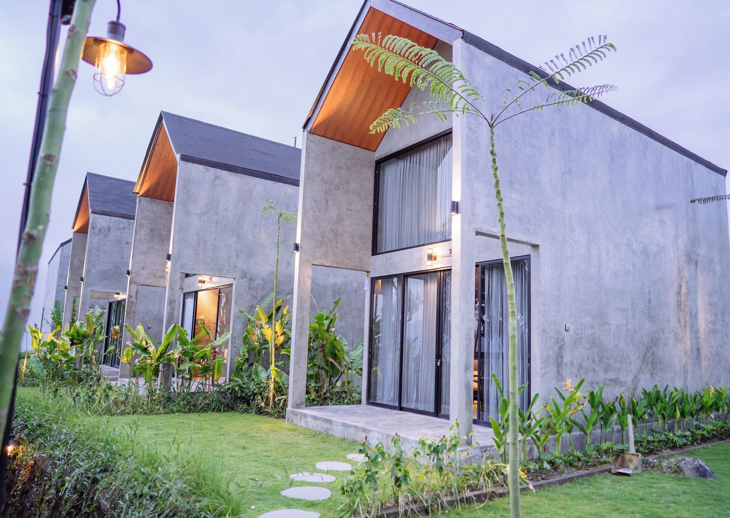 A modern building with a concrete facade, large windows, and a well-maintained garden with stepping stones.