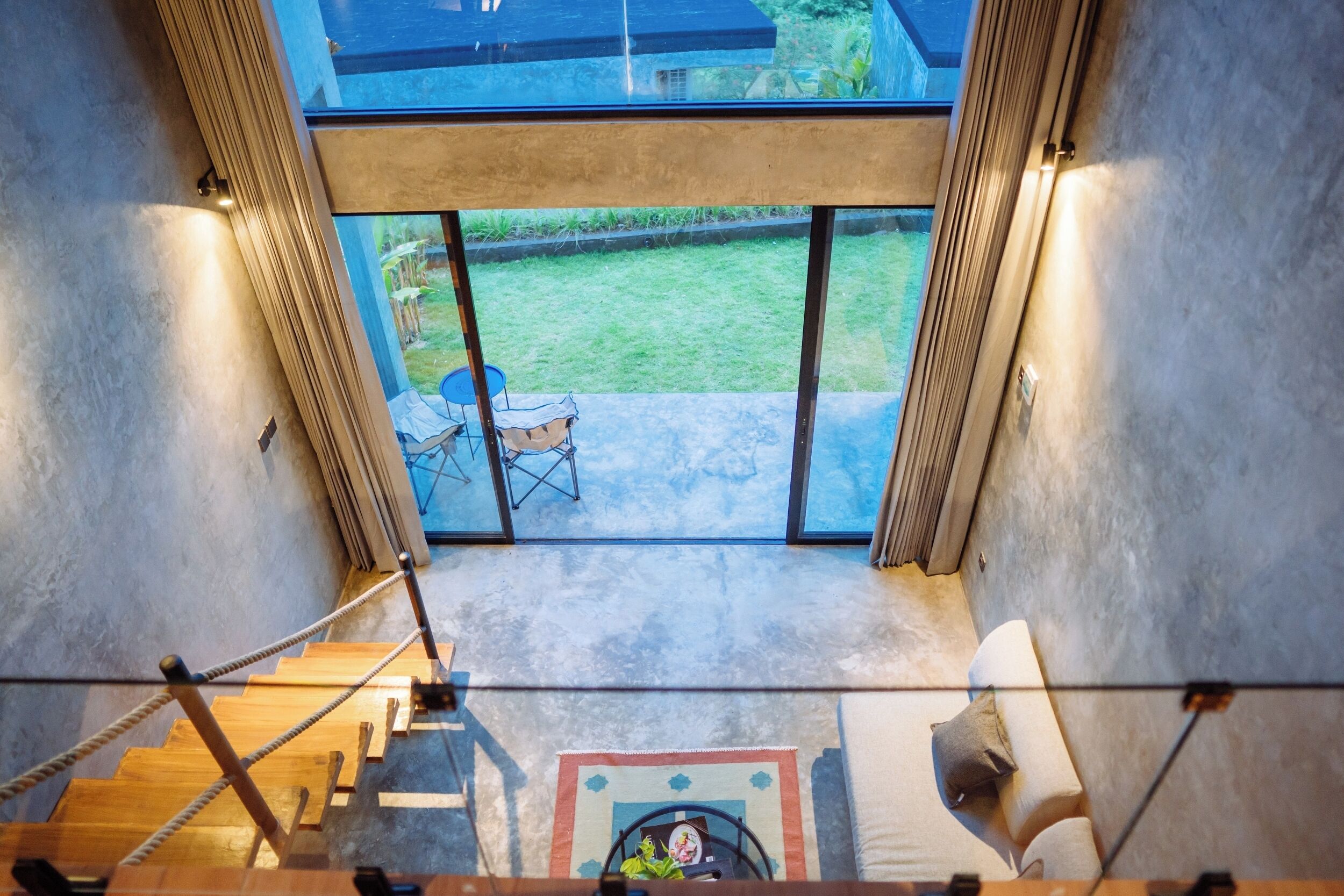 Un interior moderno con una escalera que conduce a una puerta de cristal, una pequeña mesa y una silla afuera.
