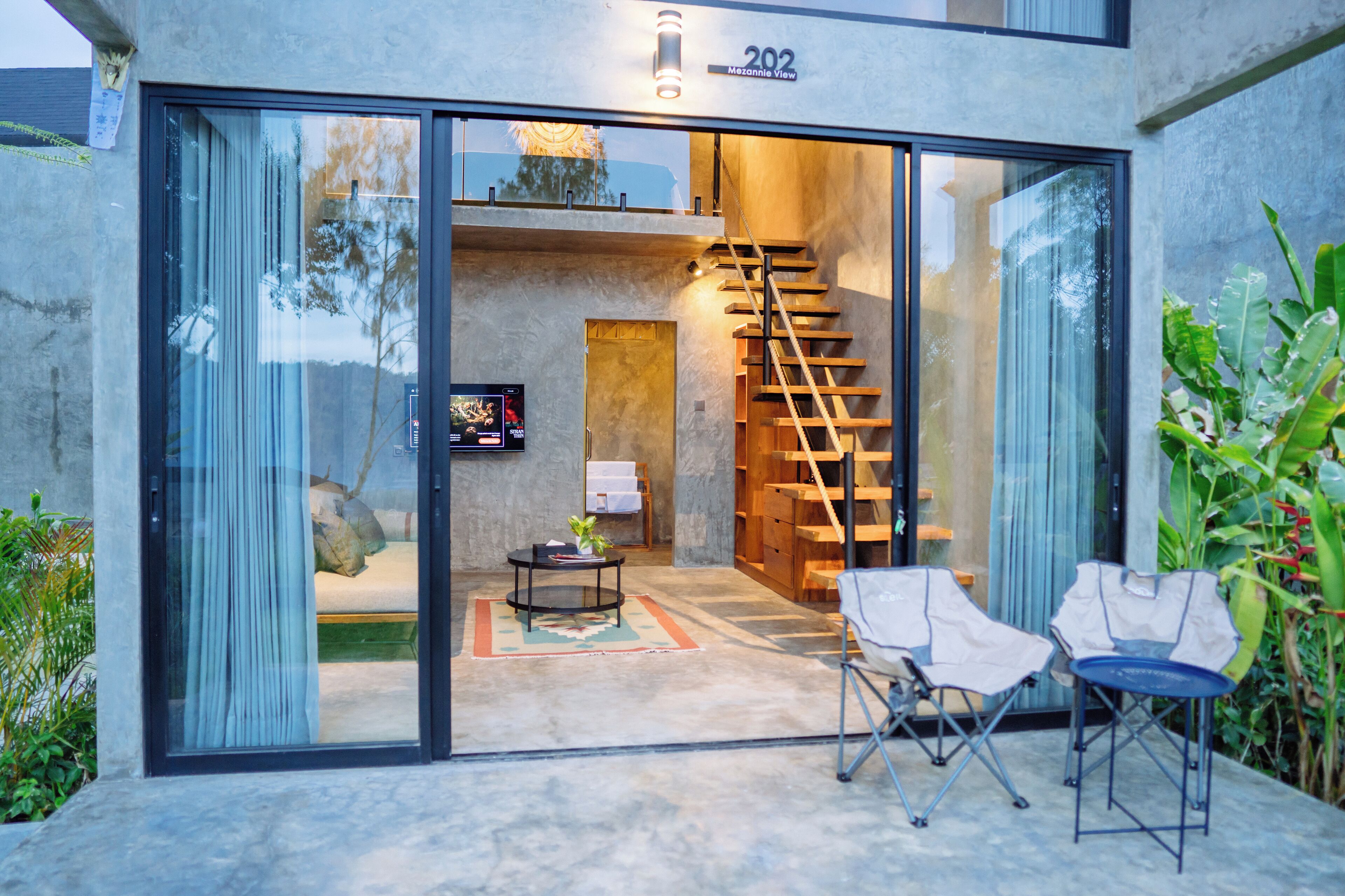 Une maison moderne avec une porte vitrée donnant sur un espace de vie comprenant un canapé, une table basse et un escalier.