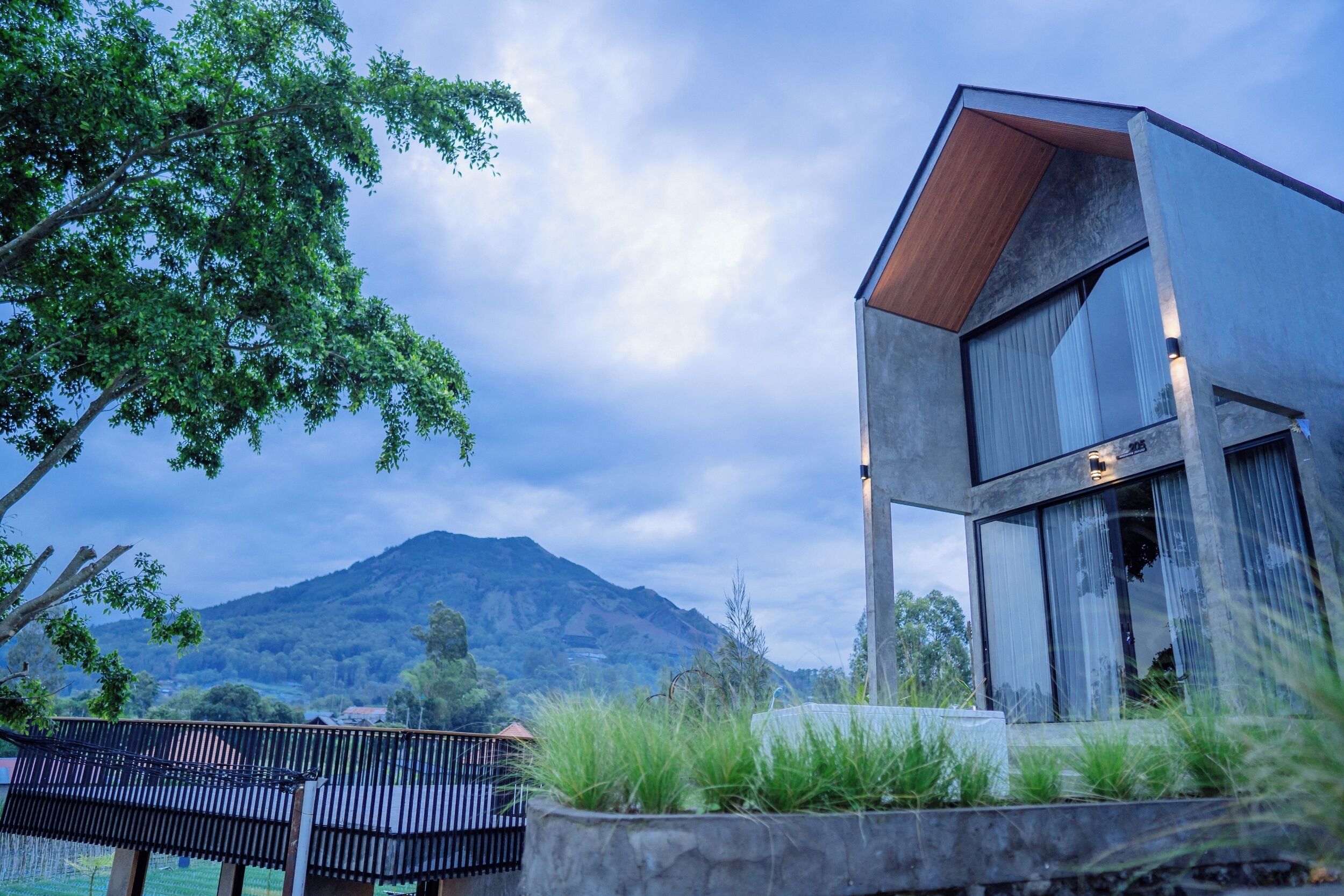 Una casa moderna con un ventanal grande y vista a la montaña.