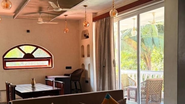 Amplia sala de estar con un conjunto de sofás, una mesa de comedor y un ventanal con vistas al verdor.