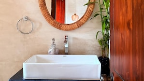 Un baño con un lavabo blanco, un espejo redondo y un mueble de madera.