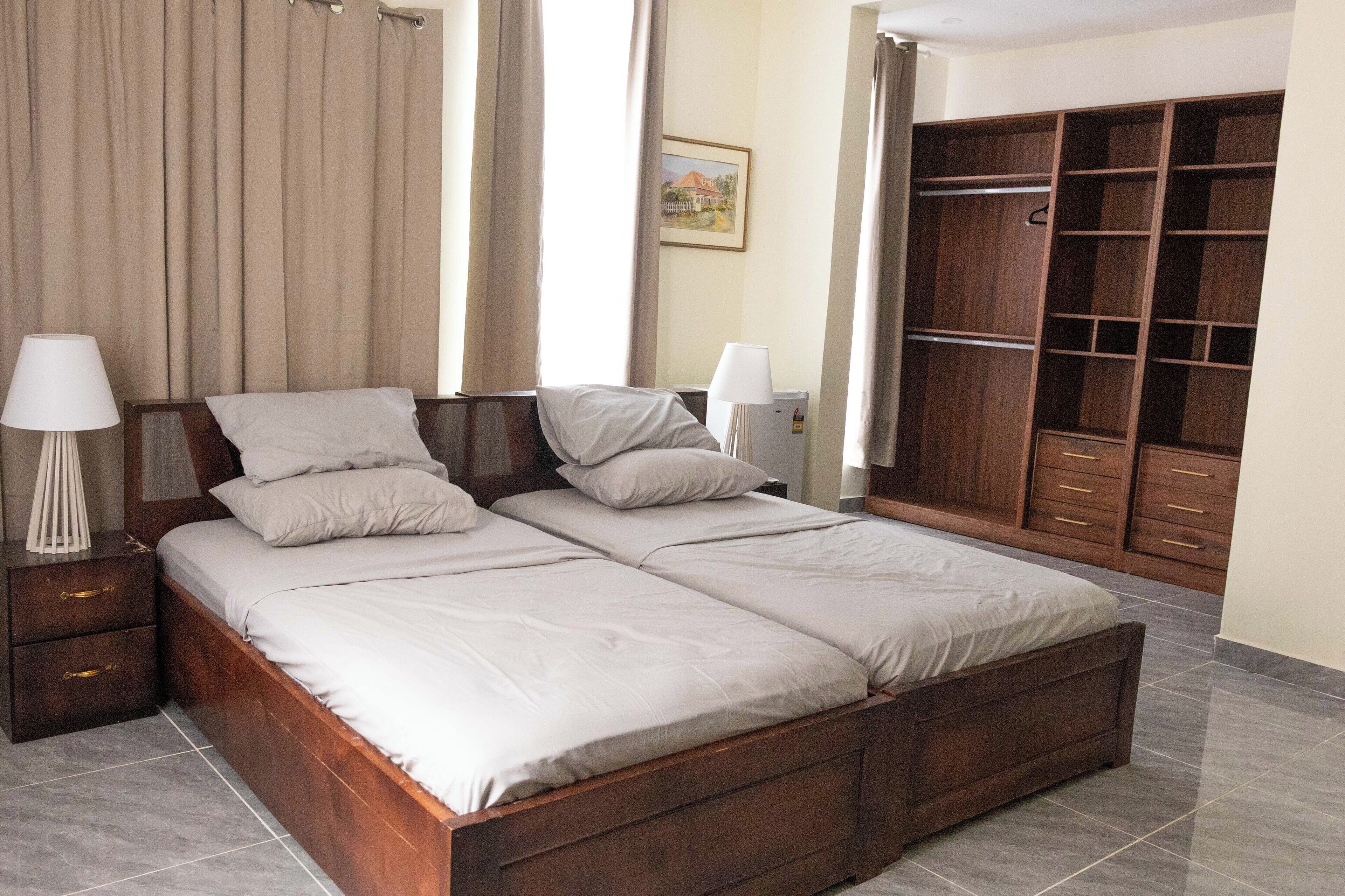 A bedroom with a wooden bed, two bedside tables with lamps, a wardrobe, and a framed picture on the wall.