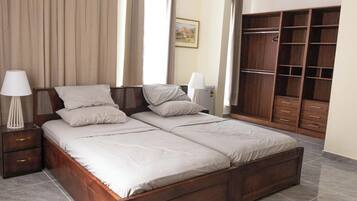 A bedroom with a wooden bed, two bedside tables with lamps, a wardrobe, and a framed picture on the wall.