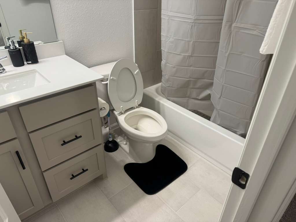 Een badkamer met toilet, wastafel en bad.