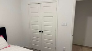 A bedroom with a bed, a white wardrobe, and a door leading to another room. - Comfy gem (Richmond)