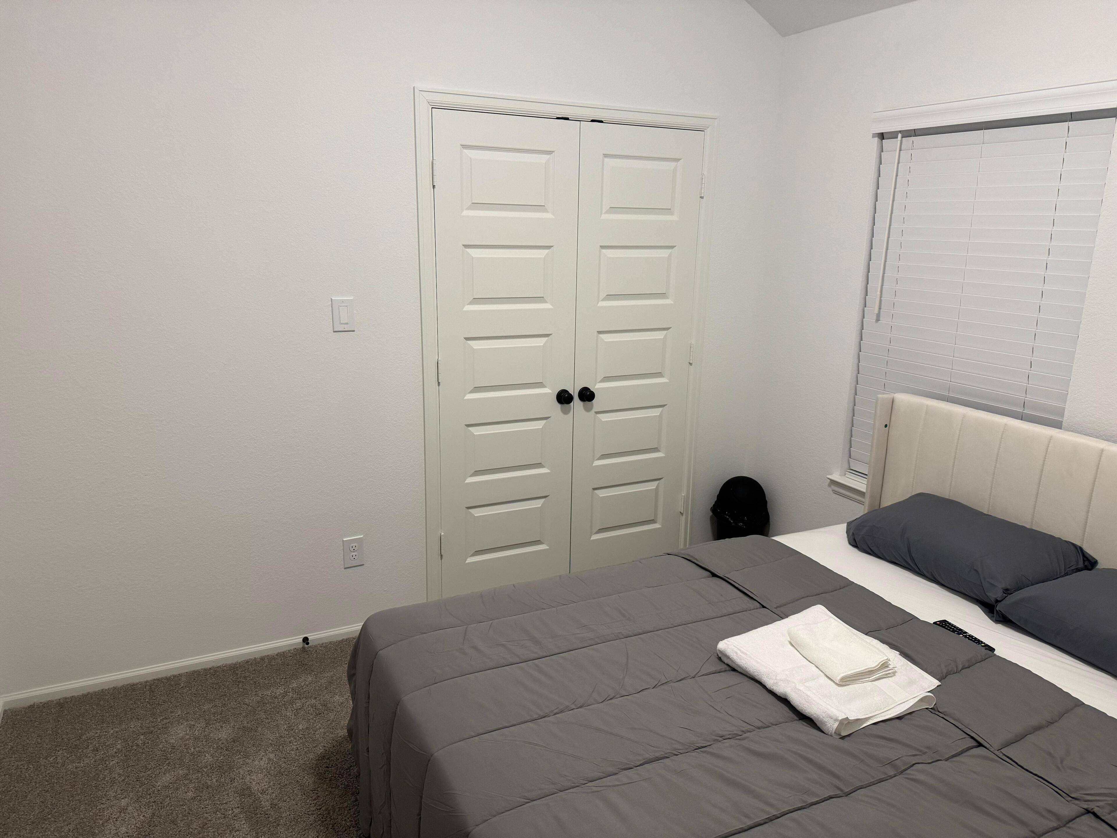 A bedroom with a bed, a closet, and a window with blinds.