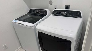 A laundry room with two front-loading washing machines and a dryer. - Comfy gem (Richmond)