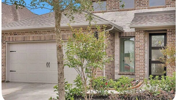 A two-story house with a garage, a small tree, and a garden. - Comfy gem (Richmond)