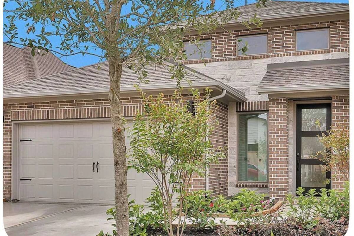 A two-story house with a garage, a small tree, and a garden.