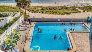 Ein Poolbereich mit mehreren Pools, Liegestühlen und Blick auf den Strand.