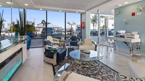 Eine moderne Hotellobby mit einem Glastresen, bequemen Sitzgelegenheiten, einem Couchtisch und Blick auf den Parkplatz.
